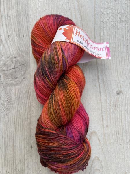 Dieses Garn wurde moeglichst farbecht fotografiert. Je nach Bildschirm koennen die Farben abweichen. Farbtoene in Worten beschrieben: kraeftiges Pink, intensives Rot, Orange, Bordeaux und dunkle Brauntoene.  ALT-Texte fuer Screenreader: 	1.	Ein Strang Wol